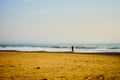 A lonely man wanders along a deserted sandy beach.