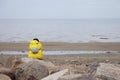 A lonely man in a yellow jacket sits on a stone alone and looks at the sea. Privacy concept in nature