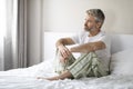 Lonely middle aged man sitting on bed, looking through window Royalty Free Stock Photo