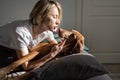 Lonely middle-aged woman embraces favourite dog lying sick on double bed at home Royalty Free Stock Photo