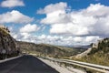 Lonely and moody road with clouds and an interesting light. Mountain road with dramatic colourful sky. Journey, outdoor, travel