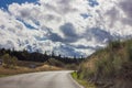 Lonely and moody road with clouds and an interesting light. Mountain road with dramatic colourful sky. Journey, outdoor, travel