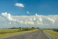 Lonely motorcyclist rides on a country road, with a sky with many clouds