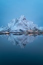 Lonely mountain perfectly reflected in cold, calm waters of northern fjord