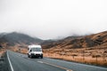 lonely moving van driving along a long narrow lonely road with no traffic between mountains and countryside with little