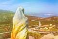 A lonely Muslim woman traveler in a colorful scarf sits on top of a mountain