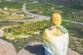 A lonely Muslim woman traveler in a colorful scarf sits on top of a mountain