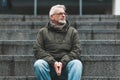 Lonely old man. A gray-haired man with wrinkles sits outside, sad. Lost a loved one, negative thoughts and depression Royalty Free Stock Photo