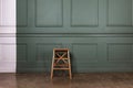 A lonely old wooden stool stands against the background of a white-green painted wall. The concept of minimalism Royalty Free Stock Photo