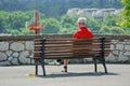 Older man is sitting alone on the bench.