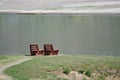 Lonely Pair of Wooden Benches Waiting Patiently Beside the Water Royalty Free Stock Photo