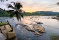 Lonely palm tree with wide angle rocky river sunset landscape with jungle banks in Pinnawala Elephant Orphanage