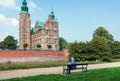 Lonely person on bench near towers of Rosenborg Castle, built in 17th century in Copenhagen. Social distancing of people