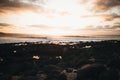 Lonely person sitting on a rock enjoying the beautiful view of the sunset reflecting on the sea Royalty Free Stock Photo