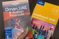 Lonely Planet Travel books in hand of Oman, UAE and Arabian Peninsula and Southeast Asia