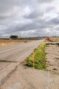 Lonely, poorly maintained road with roadwork signs under a cloudy sky. Royalty Free Stock Photo