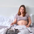 Lonely pregnant woman lies in bed next to her pet