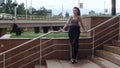 Lonely pretty girl female standing on stairs wind flowing hair in a city street