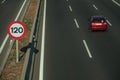 Lonely red car on highway and SPEED LIMIT sign in Madrid