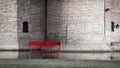 Lonely red wooden bench against a brick wall of old castle building and moat Royalty Free Stock Photo