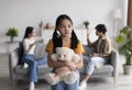 Lonely sad chinese teen girl with toy suffers from scandal of parents, young asian lady and guy quarreling at home Royalty Free Stock Photo