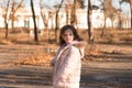 A lonely sad girl in a jacket with a fluffy hood turns around and looks to the side. Child in warm clothes in a cold autumn park Royalty Free Stock Photo