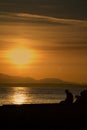 A lonely sad man sitting alone at the beach during sunset. Shot at the Golden Gardens Park in Seattle, Washington. Royalty Free Stock Photo