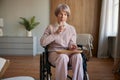 Lonely sad old woman in wheelchair taking prescribed pills at hospice