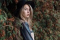 Lonely sad pretty cute blond girl with blue eyes and full lips in black hat and coat walking in autumn forest Royalty Free Stock Photo