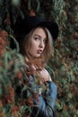 Lonely sad pretty cute blond girl with blue eyes and full lips in black hat and coat walking in autumn forest Royalty Free Stock Photo