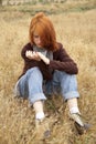 Lonely sad red-haired girl at field