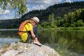 lonely sad teenager girl dreams sitting on stone shore. girl sitting in life jacket near the water, river, lake. concept of Royalty Free Stock Photo