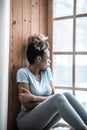 Lonely sad woman looking out window on windowsill Royalty Free Stock Photo