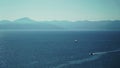 Lonely Sail boat sailing through the vast ocean with mountains on the horizon. Royalty Free Stock Photo