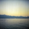 A lonely sailing boat on the Lake Leman in Lausanne Switzerland with background of the Alps, shot with analogue color film Royalty Free Stock Photo