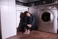 Lonely scared and sick woman sitting on kitchen floor in stress depression and sadness