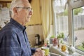 Lonely Senior Man Looking Unhappy Out Of The Window Holding Cup Royalty Free Stock Photo