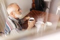 Lonely senior man sitting at kitchen table drinking tea