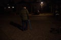 Lonely senior man walking on French street at night using walking stick