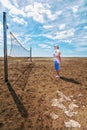 Lonely senior woman looking melancholy at a beach volleyball net Royalty Free Stock Photo