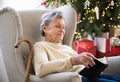 A lonely senior woman reading Bible at home at Christmas time. Royalty Free Stock Photo