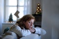 Lonely senior woman sitting and sleeping on sofa indoors at Christmas, solitude concept. Royalty Free Stock Photo