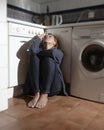 Lonely and sick woman sitting on kitchen floor in stress depression and sadness