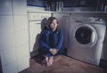 Lonely and sick woman sitting on kitchen floor in stress depression and sadness