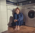 Lonely and sick woman sitting on kitchen floor in stress depression and sadness