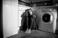 Lonely and sick woman sitting on kitchen floor in stress depression and sadness