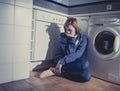 Lonely and sick woman sitting on kitchen floor in stress depression and sadness