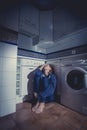 Lonely and sick woman sitting on kitchen floor in stress depression and sadness