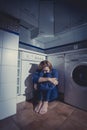 Lonely and sick woman sitting on kitchen floor in stress depression and sadness