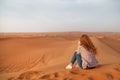 Lonely sitting redhead woman in evening desert meditating outdoors